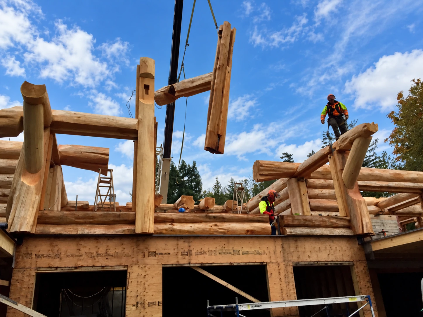 A crane lifts a heavy timber beam onto a log home under construction as builders guide the frame